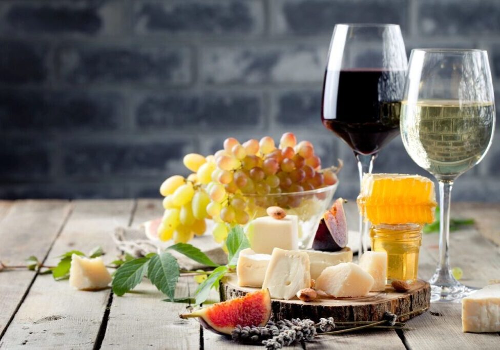A wooden table topped with wine glasses and cheese.